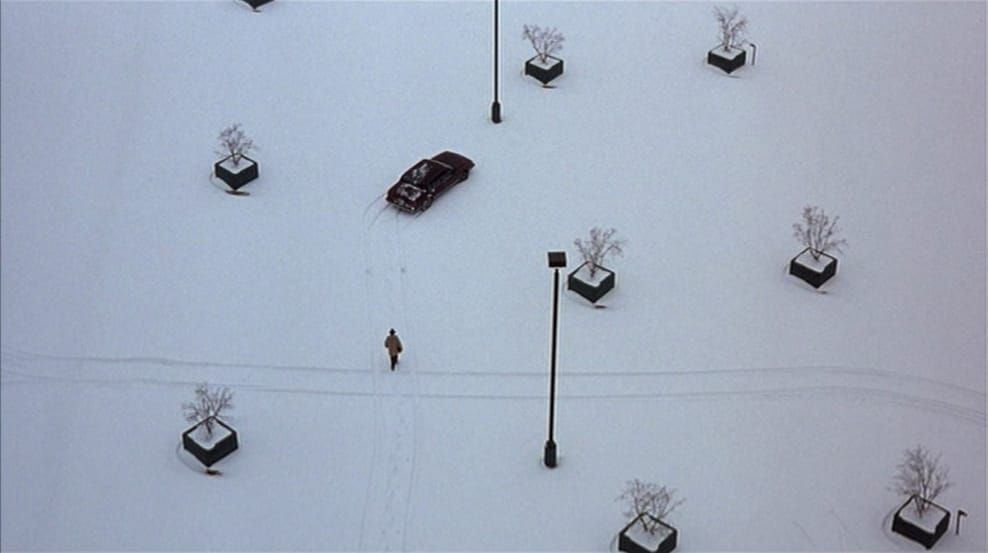 An overhead shot of a man walking to his car in a snowy parking lot
