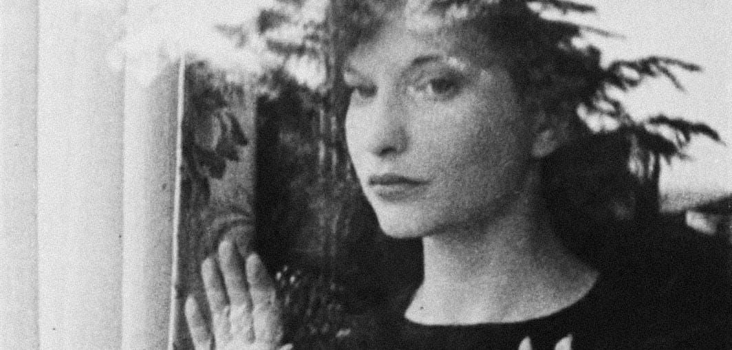 Meshes of the Afternoon: Maya Deren looks out a window toward the camera, her hand pressed to the glass.