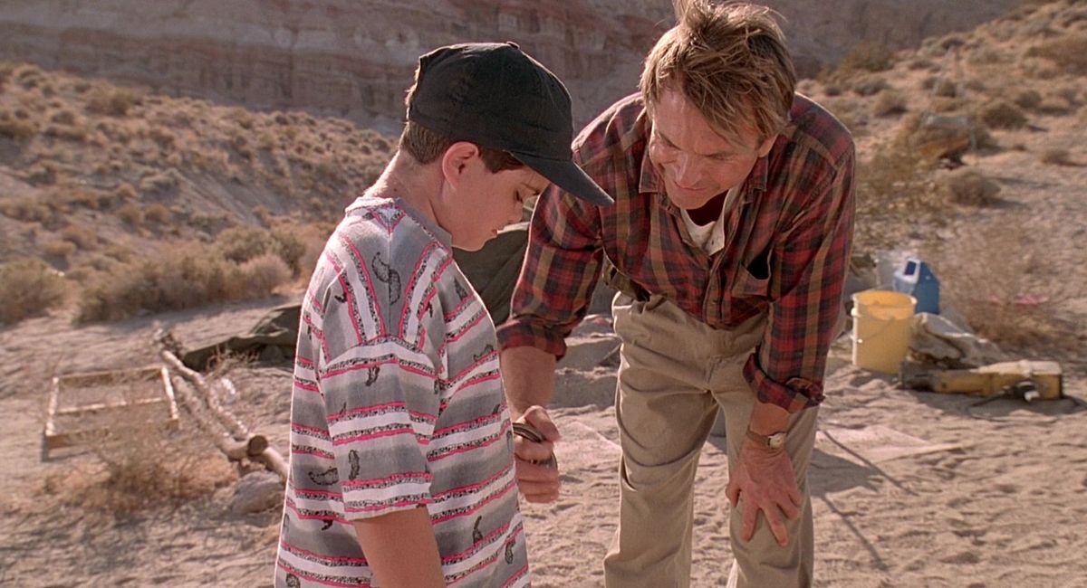 Jurassic Park: Dr. Grant at a dig site, holding a raptor claw against the belly of a terrified child.