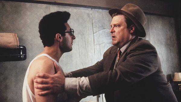 Barton Fink: Hotel room. Wallpaper peeling. Charlie Meadows holds Barton Fink by the arms, a look of desperation on his face.
