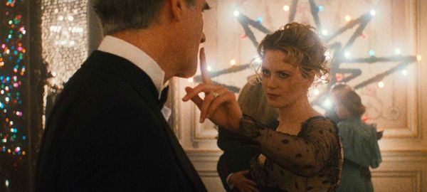 Nicole Kidman holds a finger up to a strange man's mouth with Christmas lights behind her, in a still from Eyes Wide Shut