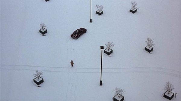 An overhead shot of a man walking to his car in a snowy parking lot