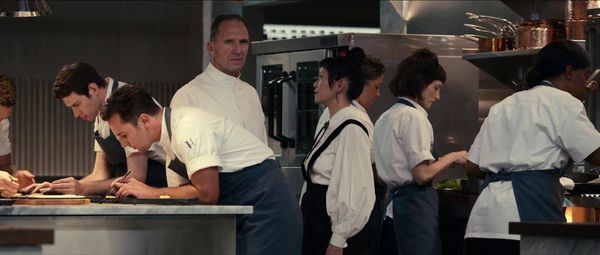 The Menu: In the kitchen surrounded by his team at work, Chef Slowik glares toward the camera while listening to Elsa.