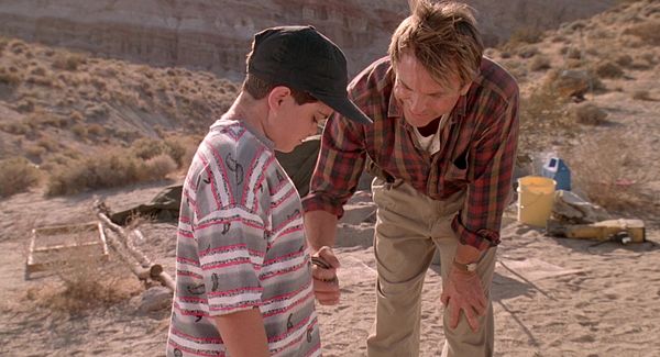 Jurassic Park: Dr. Grant at a dig site, holding a raptor claw against the belly of a terrified child.