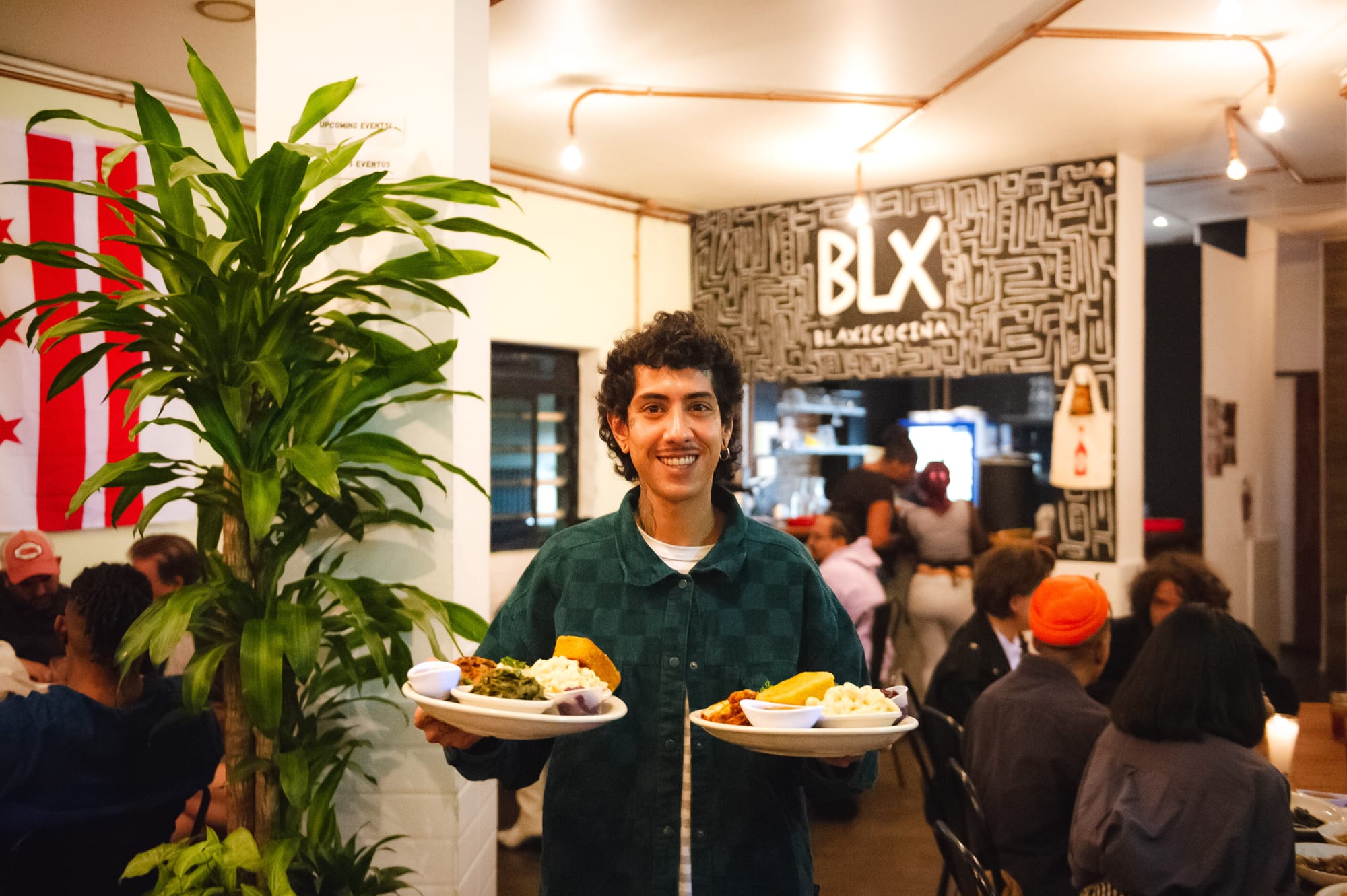 A restaurant employee holds two dishes stacked with all the fixings.