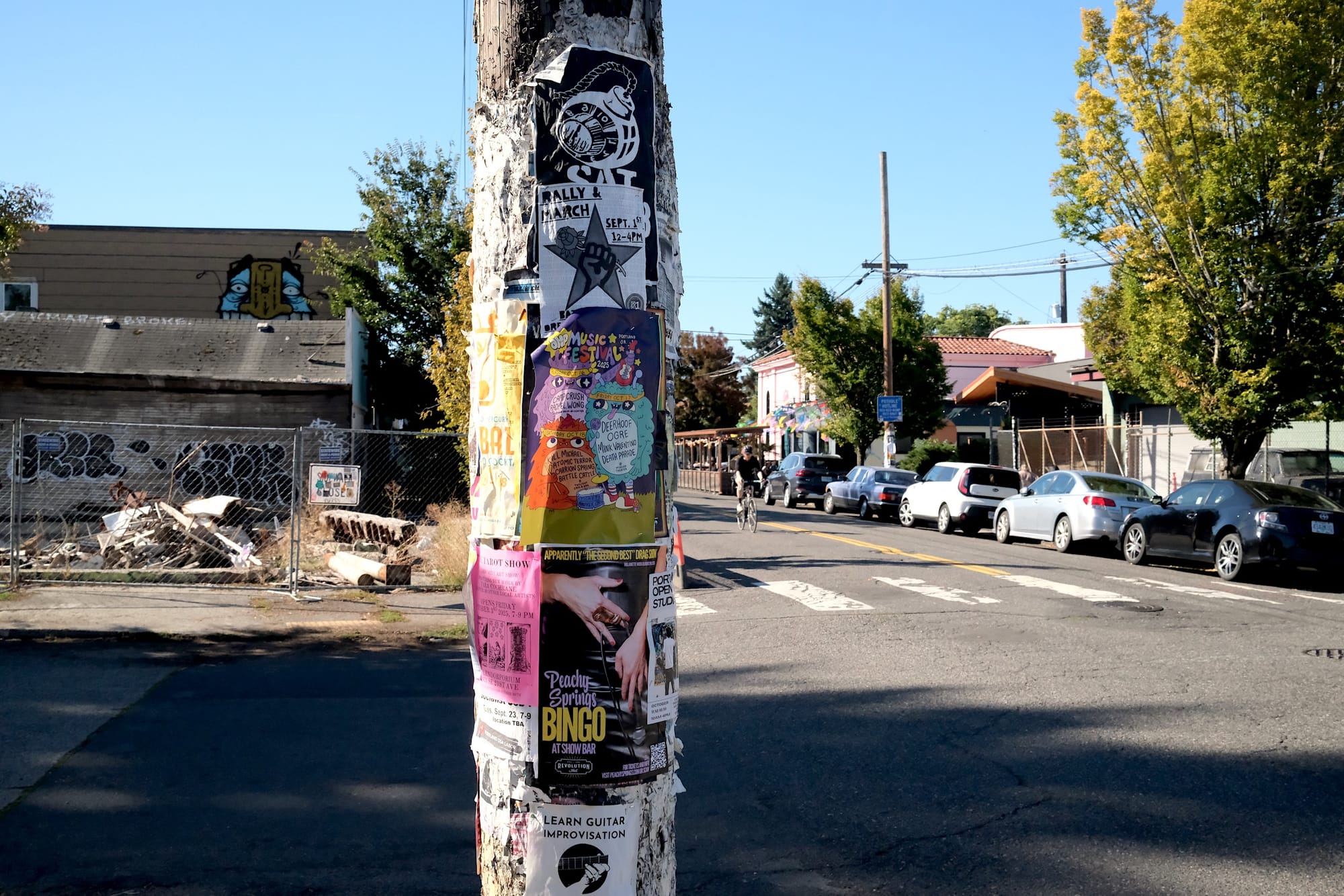A utility pole with posters for rallies, drag shows, guitar lessons, tarot readings, and more.