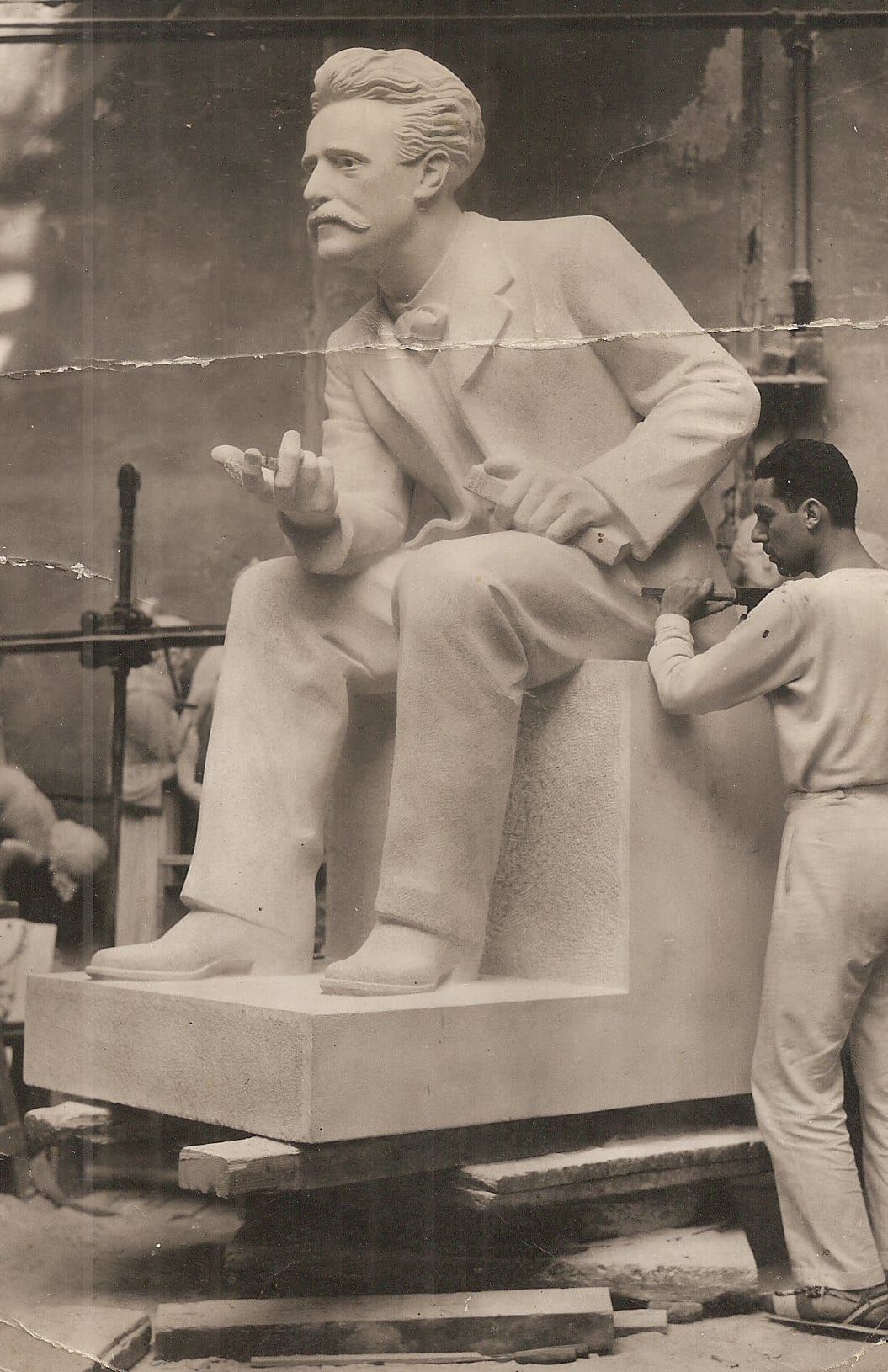 The sculptor works on a larger-than-life monument of the author Paul Lafargue sitting, leaning forward with his right hand extended and his left hand holding a book.