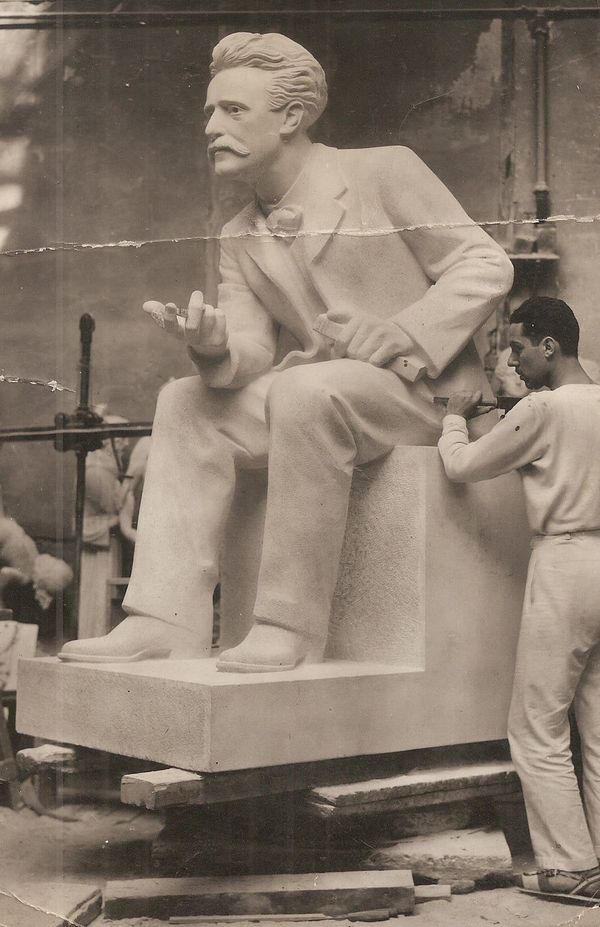 The sculptor works on a larger-than-life monument of the author Paul Lafargue sitting, leaning forward with his right hand extended and his left hand holding a book.