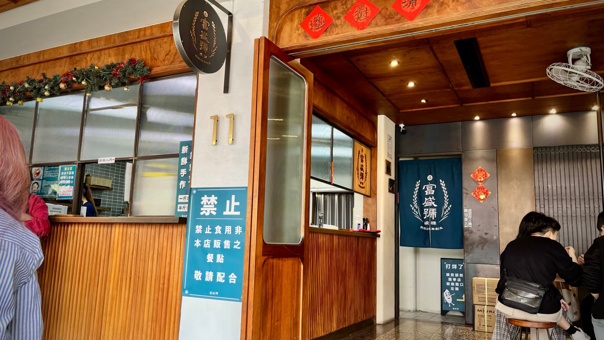 Customers eating outside a restaurant. The counter opens on to the street, with open-air stools and tables around the building.