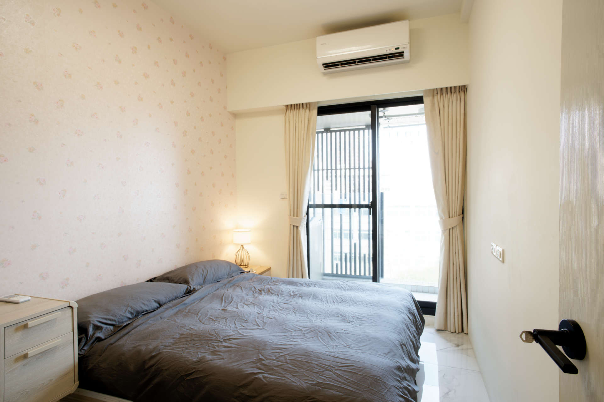 A bedroom with double bed, side table, and desk.