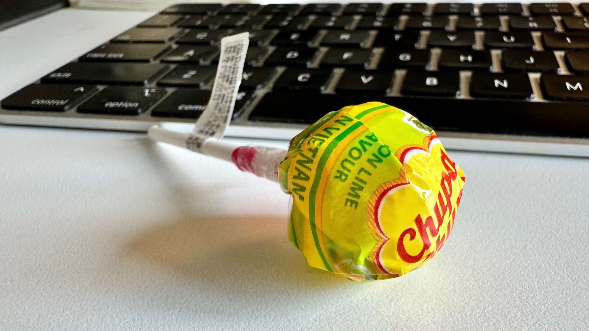 A Chupa Chup lollipop resting on a computer keyboard.
