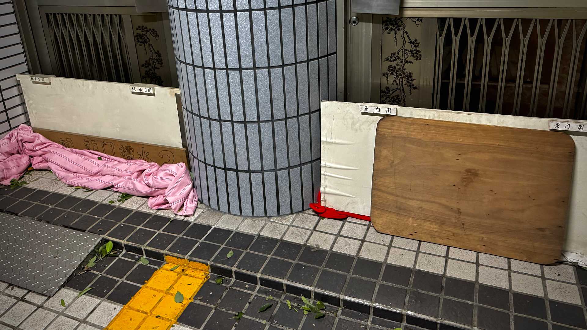Two building entrances, both blocked with vertical wooden boards, intended to stop water ingress during Typhoon Gaemi.