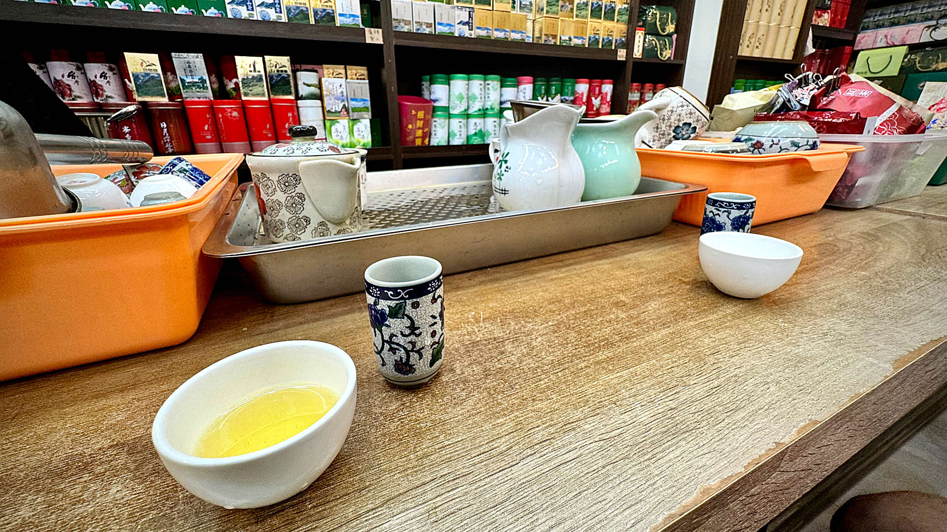 An array of boxed teas and teapots, plus two tasting cups, on a counter in a traditional Taiwanese tea shop.