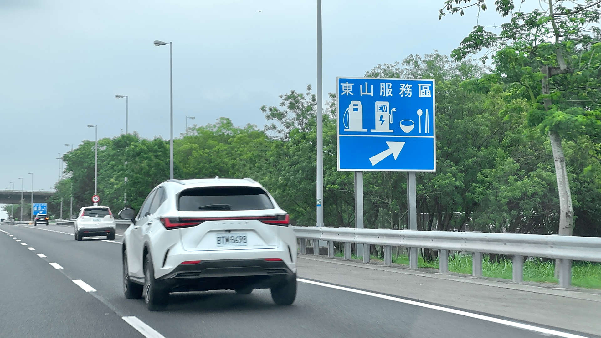 A highway sign indicating an exit for a gas station, electric vehicle charging, and restaurant.
