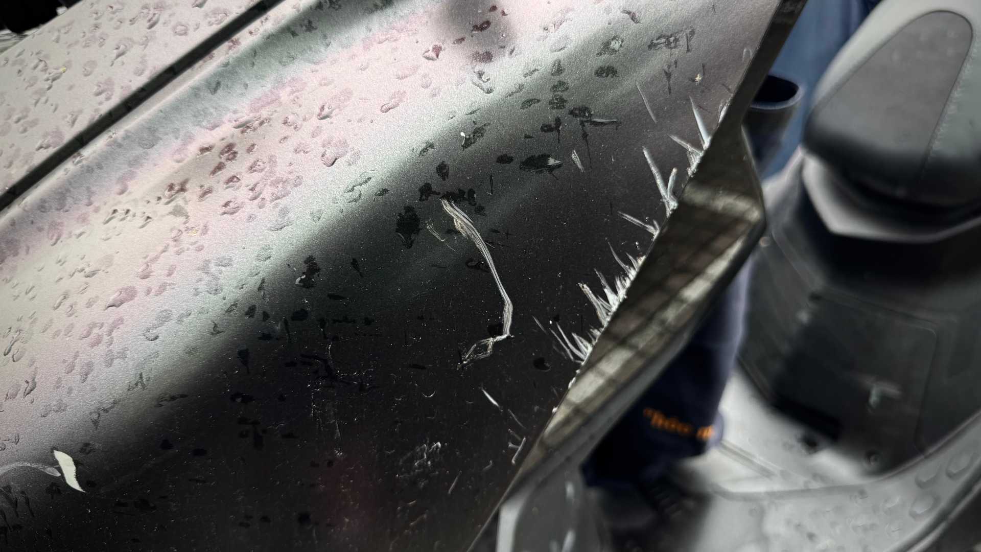 Extensive rough scratches on the front plastic panel of an MMBCU scooter.