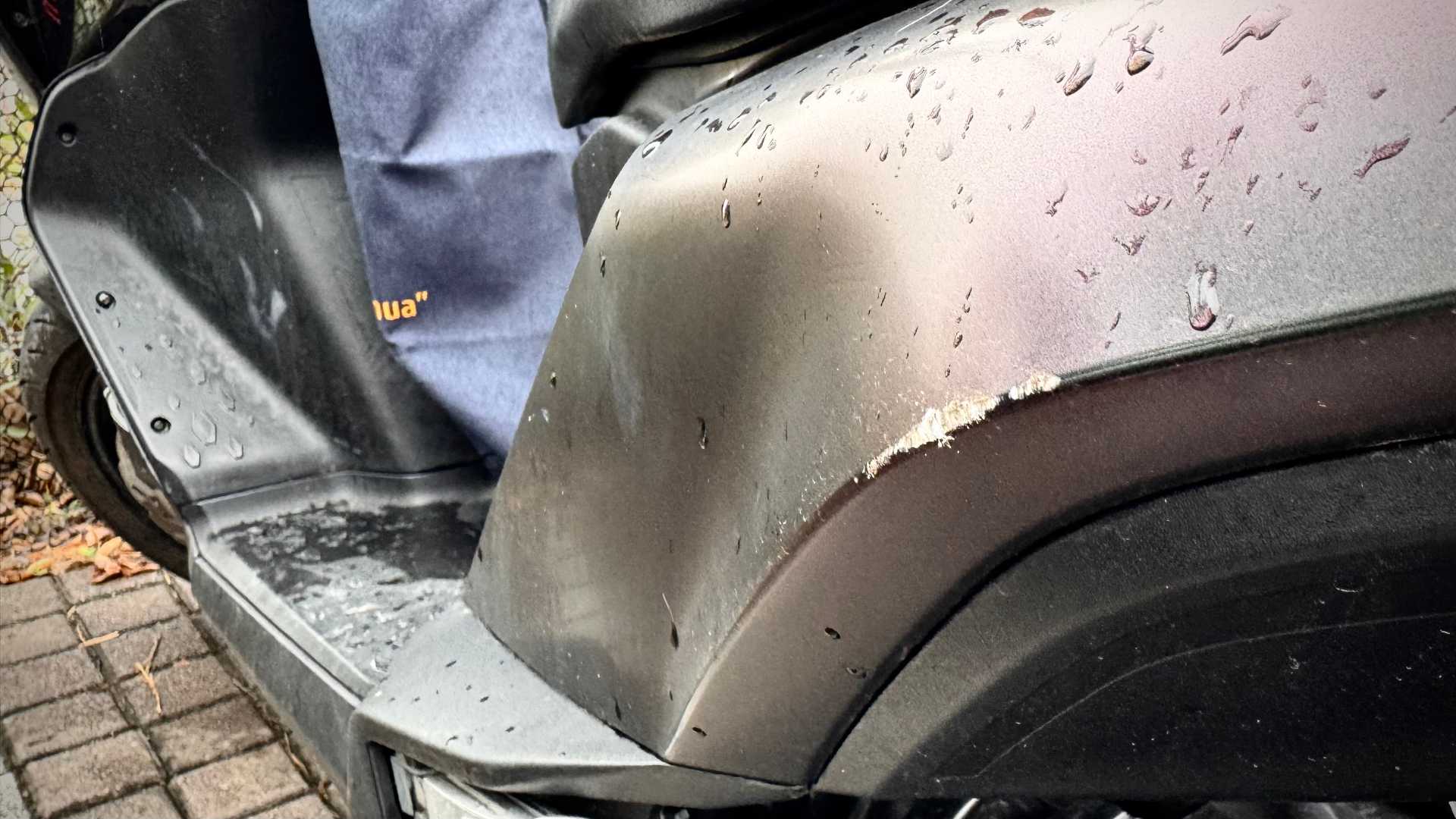 Rough scratches along the back-left body panel of an MMBCU scooter.