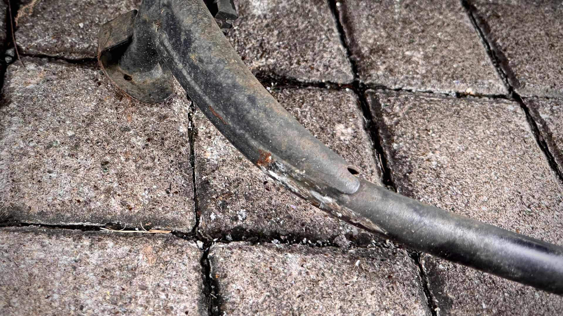 Deep scratches on a bent center stand of an MMBCU scooter.