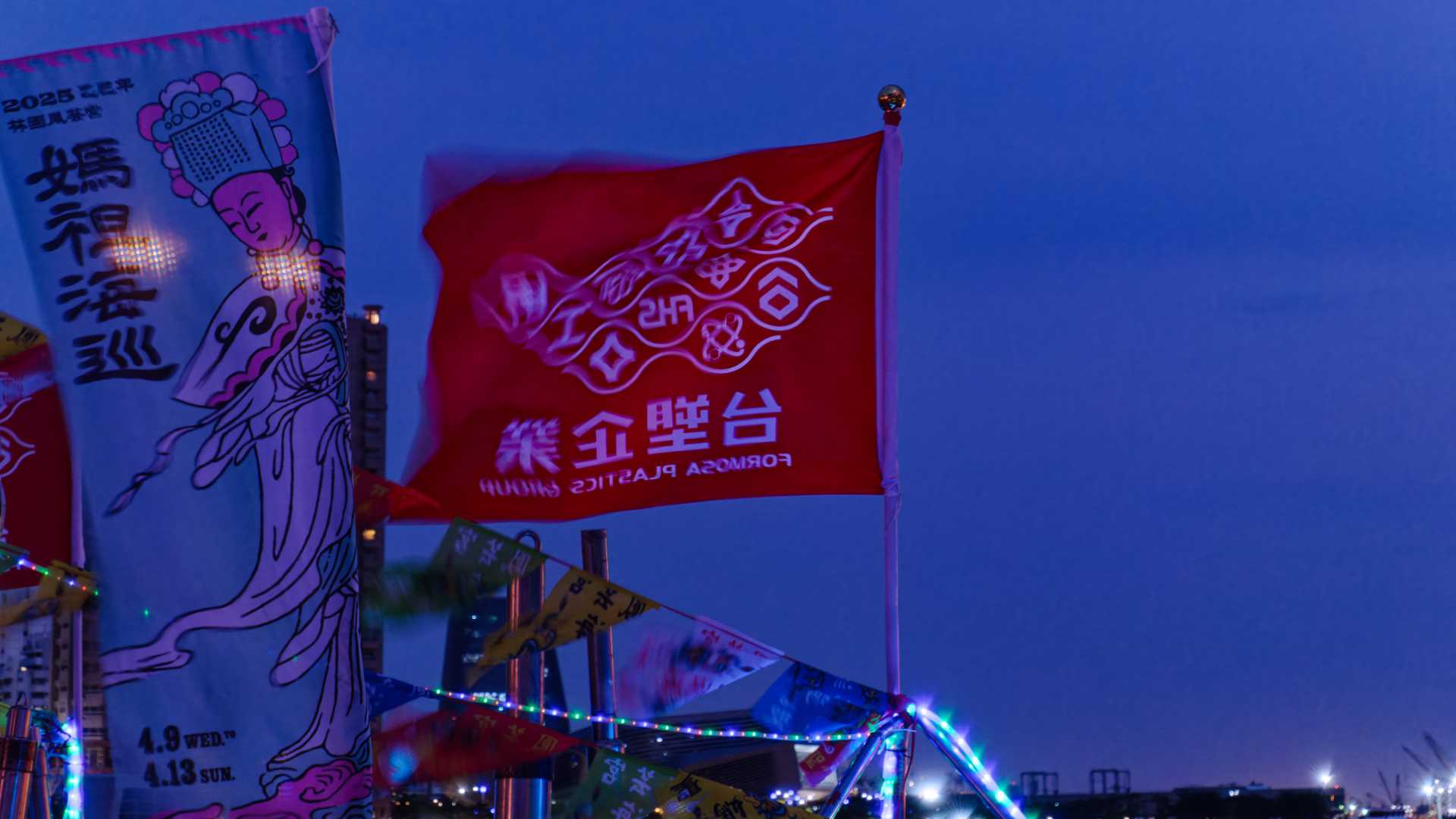 A red flag, slightly blurred from movement in the wind, that reads ‘Formosa Plastics Group’. Next to the flag, a banner promotes the Mazu Sea Patrol Rite 2025.