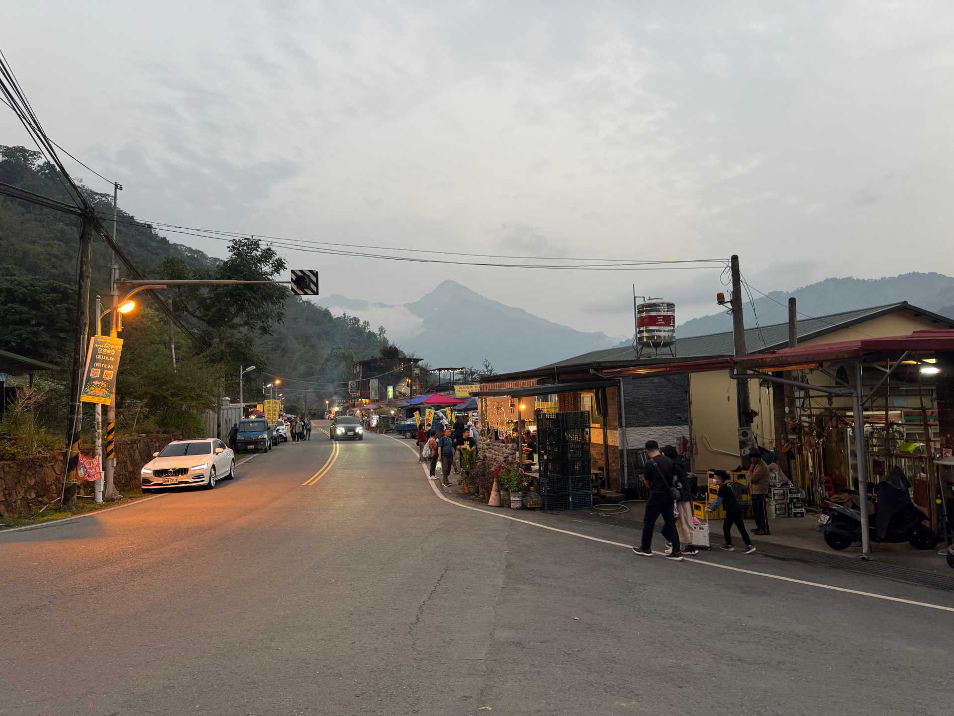 The main street of Maya Village. A series of one-storey shops and restaurants line the right-hand side. A bunch of stalls are present outside the shops in the distance.