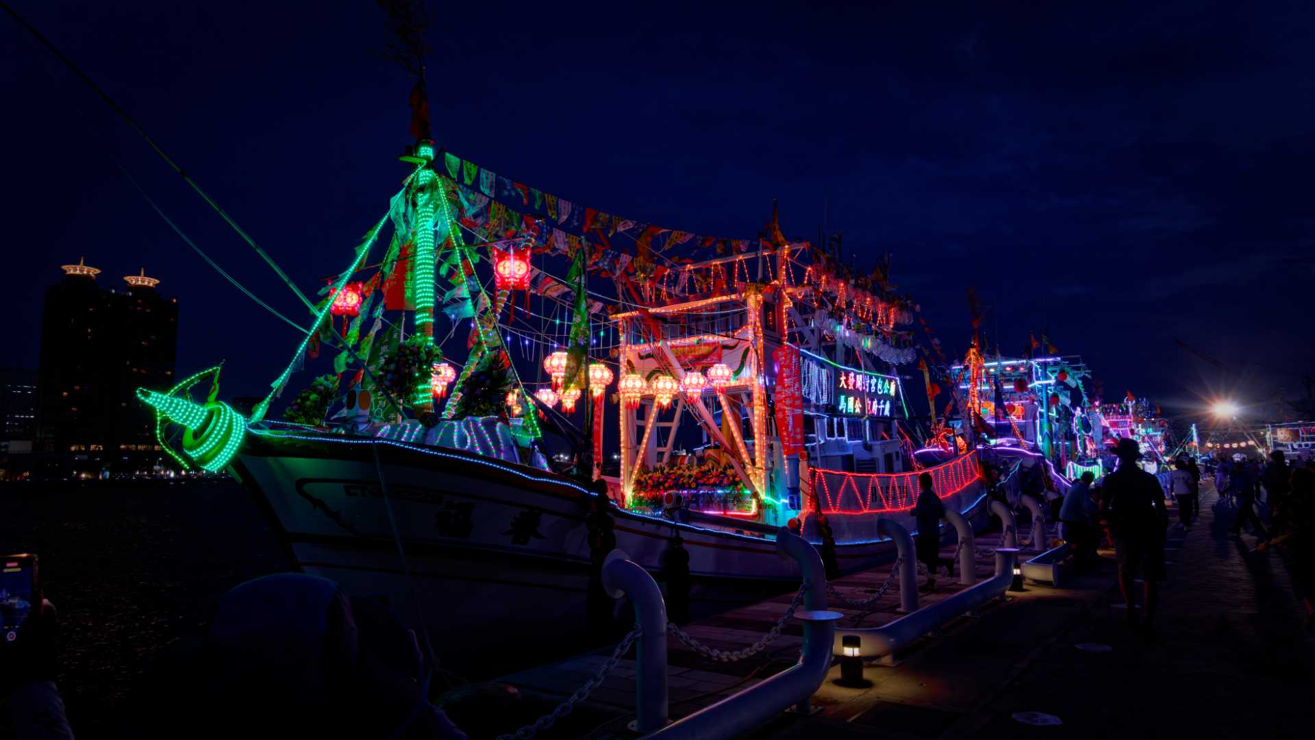 A brightly-lit and decorated squid boat, docked in Kaohsiung at night.