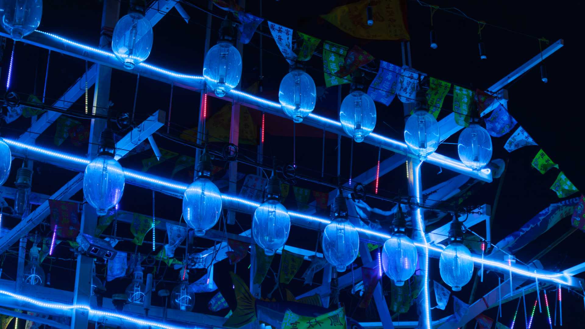 Close-up of two rows of squid lamps on a Taiwanese fishing boat. The lamps are not turned on, but are reflecting blue light from decorative LED lighting on the boat.