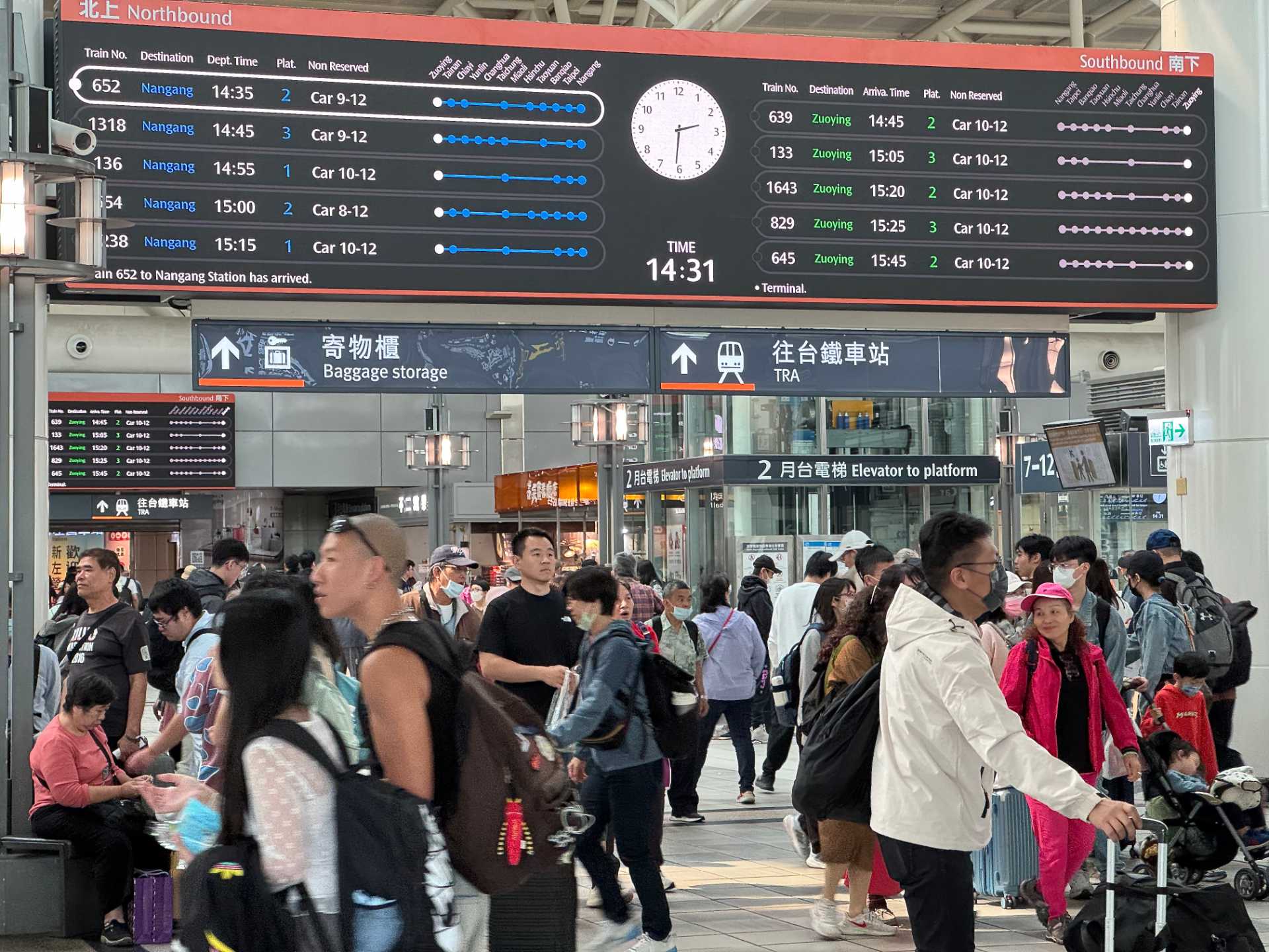 Dozens of people beneath an arrivals and departures board at Zuoying High Speed Rail Station in Kaohsiung, Taiwan.