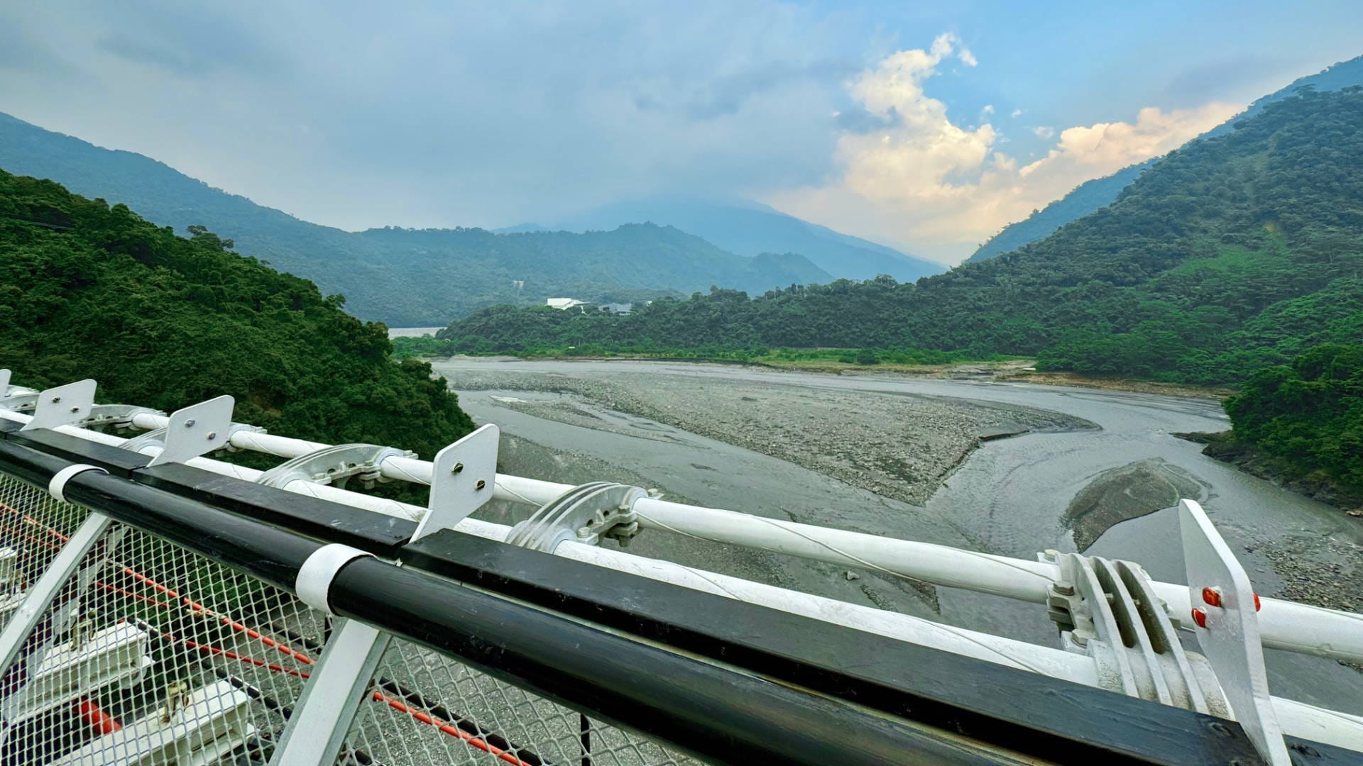 View looking up the river in a mountainous valley. Dark clouds are forming in the distance.