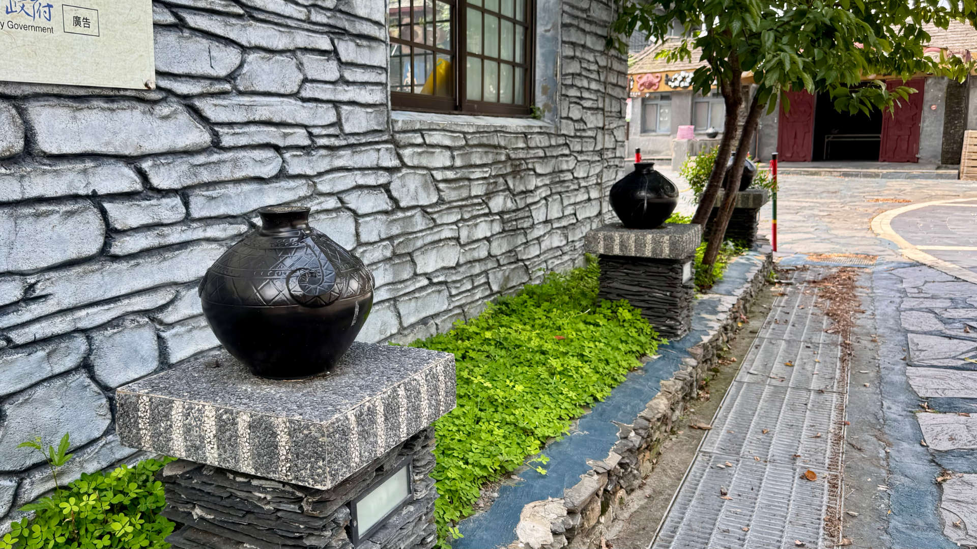 Black clay pots mounted on slate podiums outside a government building in Wutai Township, Taiwan.