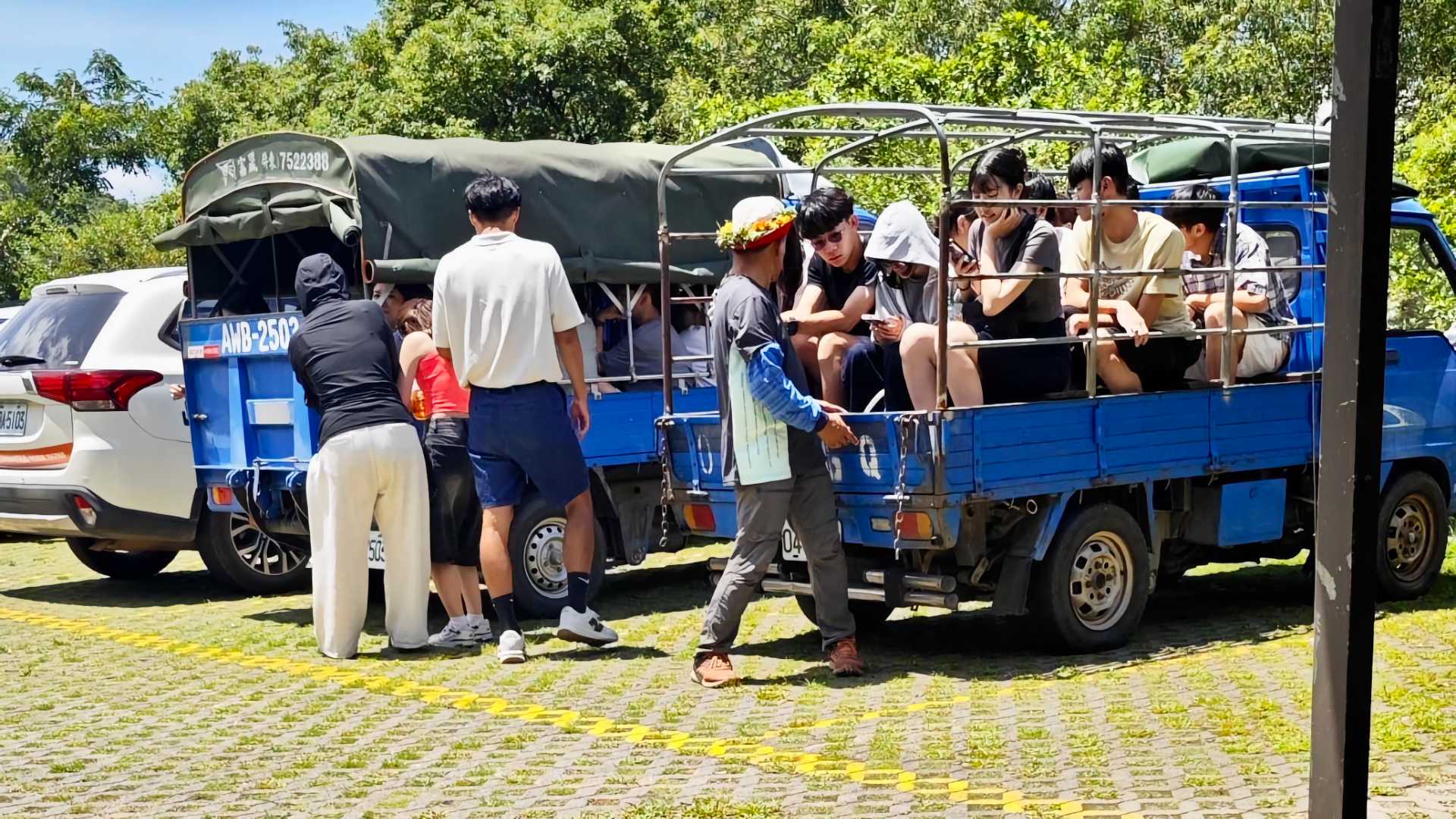 Around two dozen students crammed onto the cargo decks of two small blue trucks.