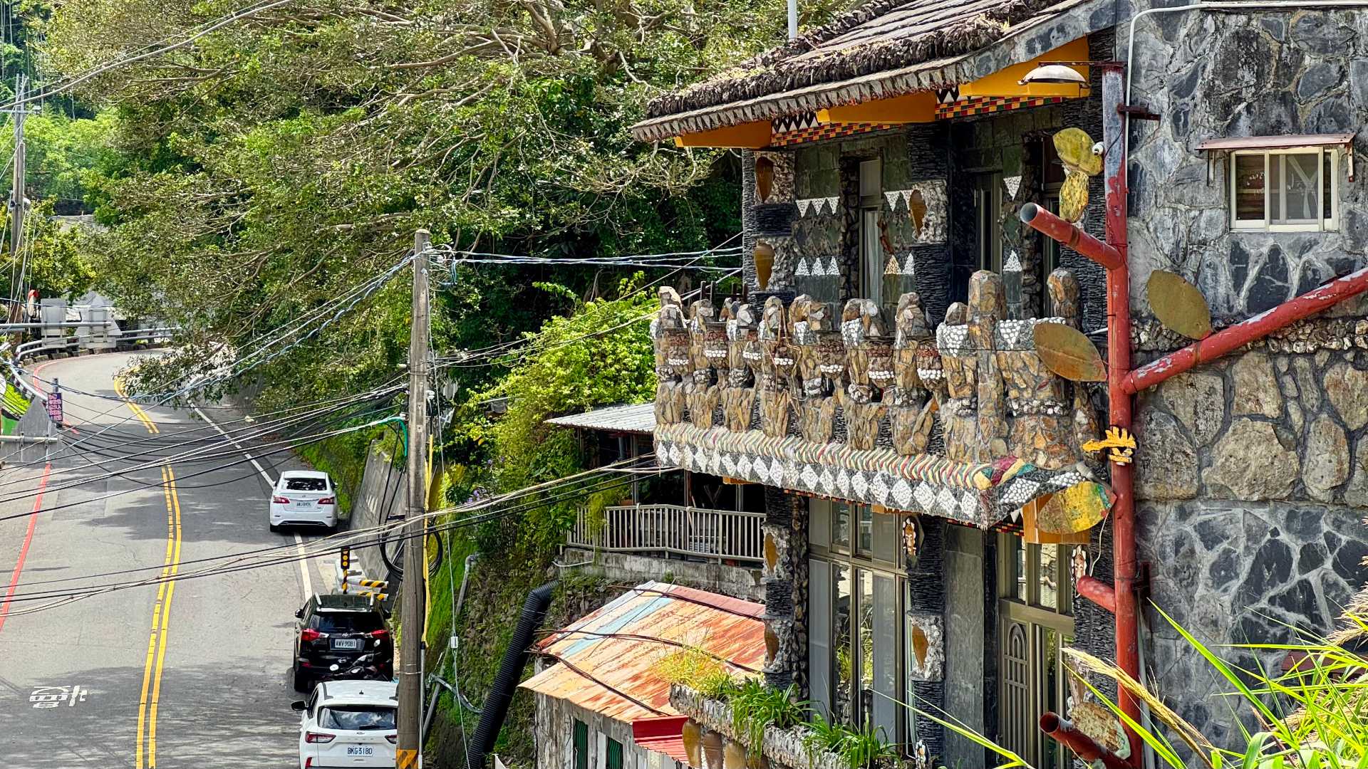 A three-story homestay house made of stone, on a street in Wutai Township, Taiwan. The balustrades are made of indigenous sculptures.