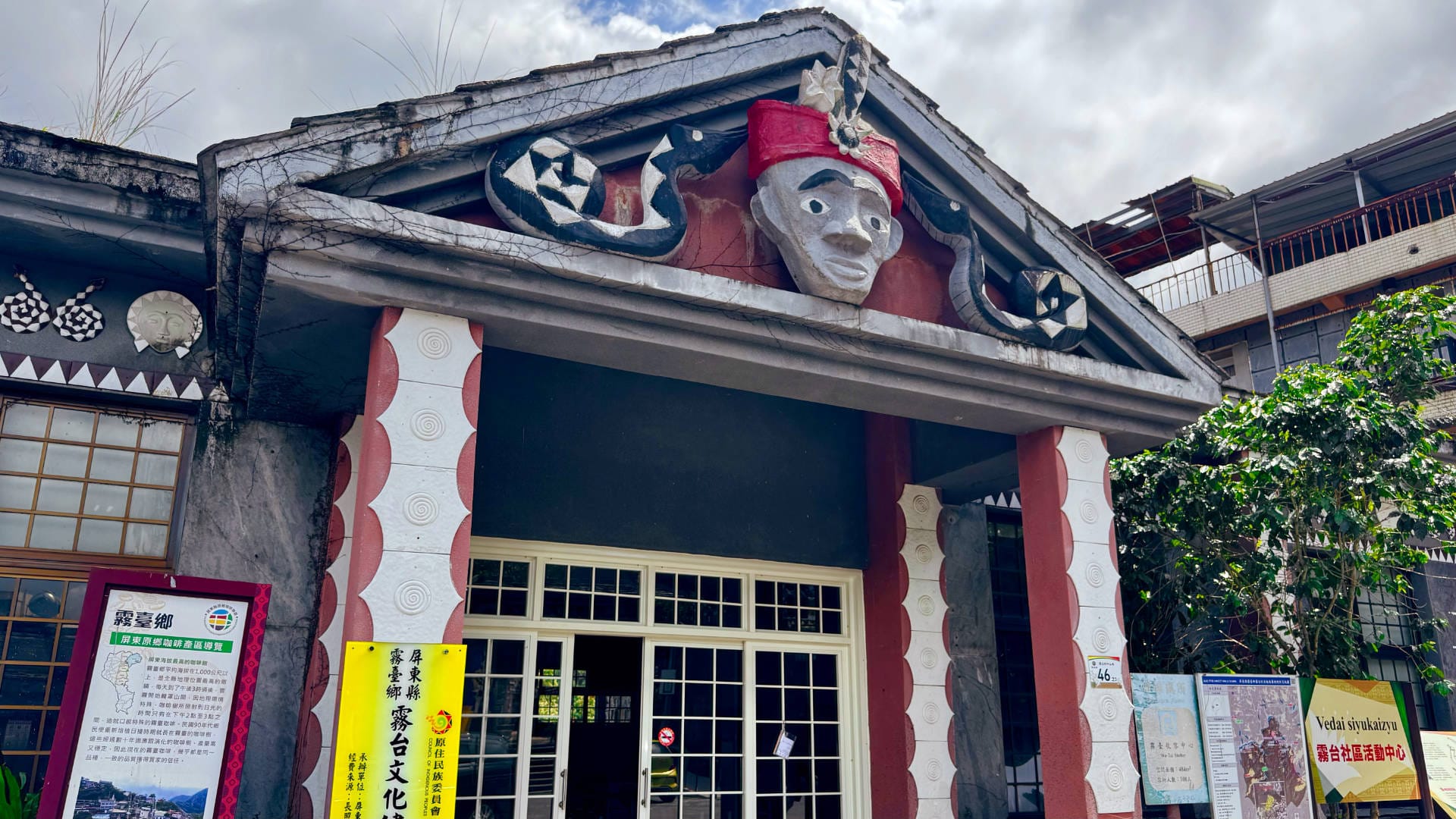 Statues of snakes and a head wearing traditional headdress above the entrance to a community health center in Wutai Township, Taiwan.