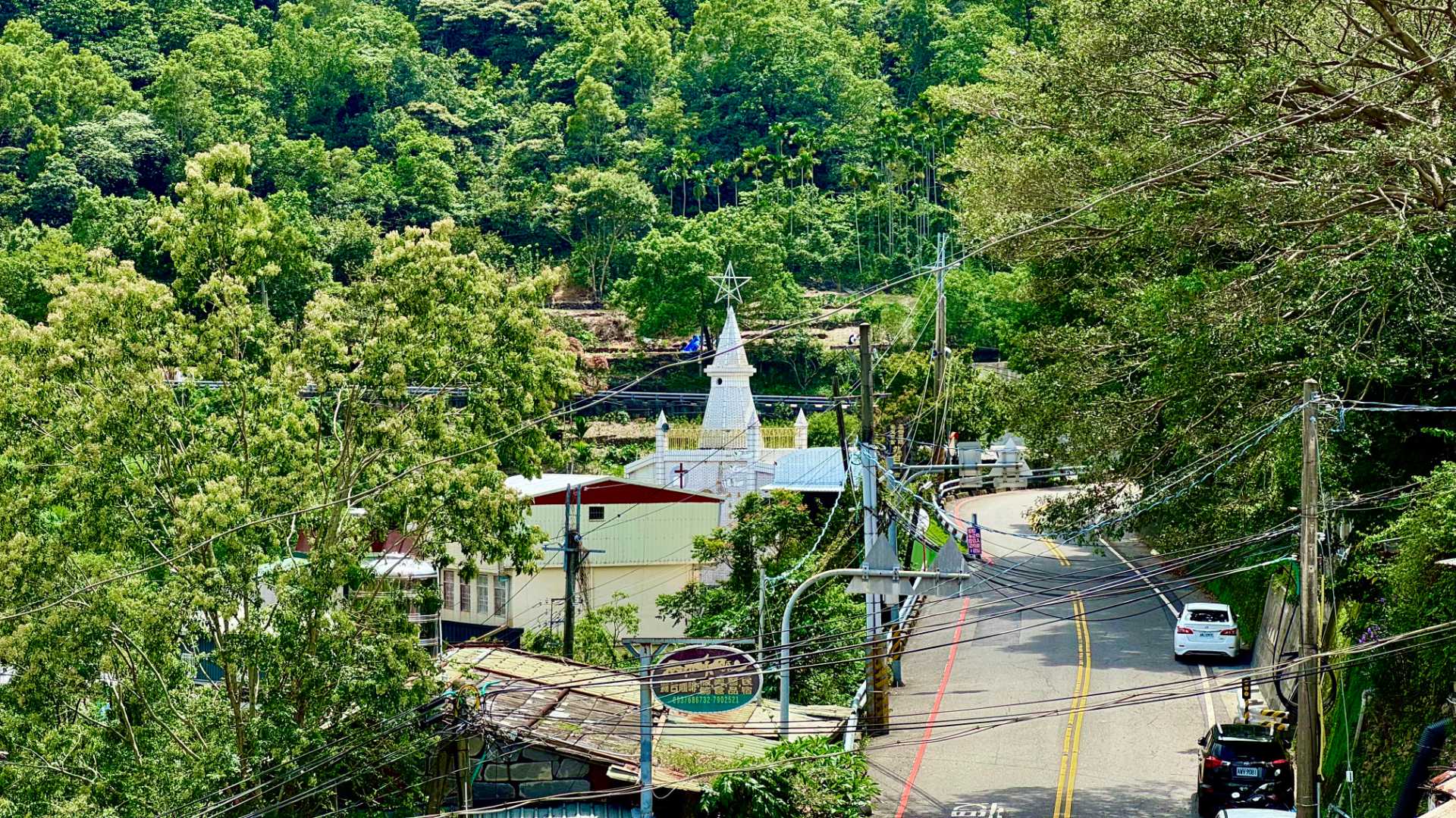 A view of a quiet street in Wutai Township. In the distance, a clean white steeple topped with a white star denotes the Seventh Day Adventist Church.