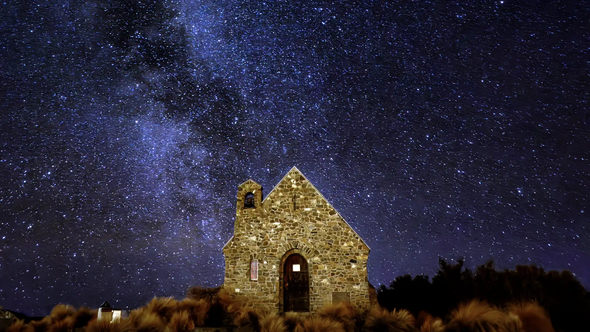 A nighttime photo of the Church of the Good Shepherd at Lake Tekapo, New Zealand, with a sky full of stars above. An optical illusion makes the Milky Way appear to be rising from the belfry, like smoke from a chimney.