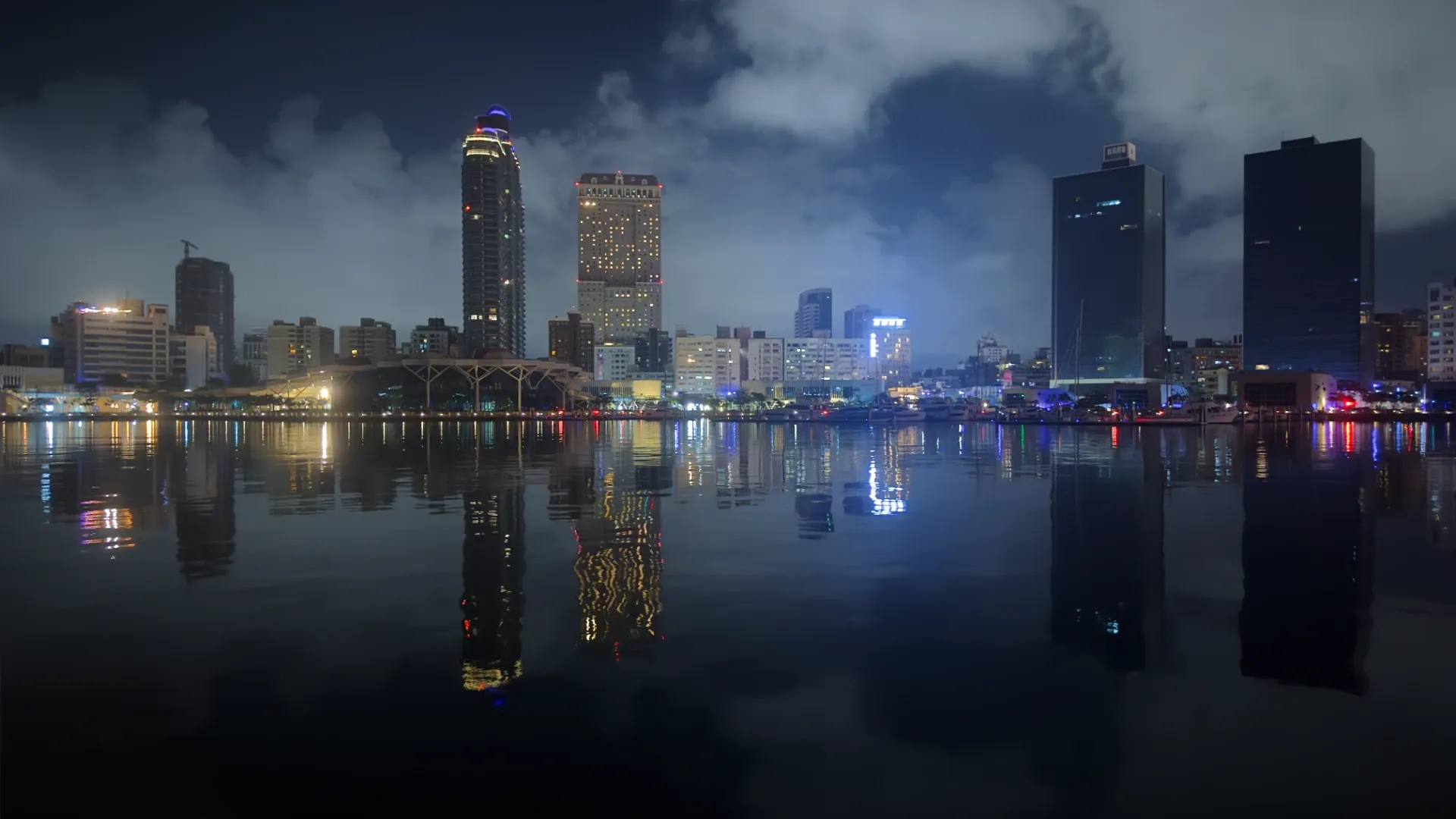 Nighttime view of the skyline of Kaohsiung City, Taiwan, with skyscrapers reflected in the calm harbor.