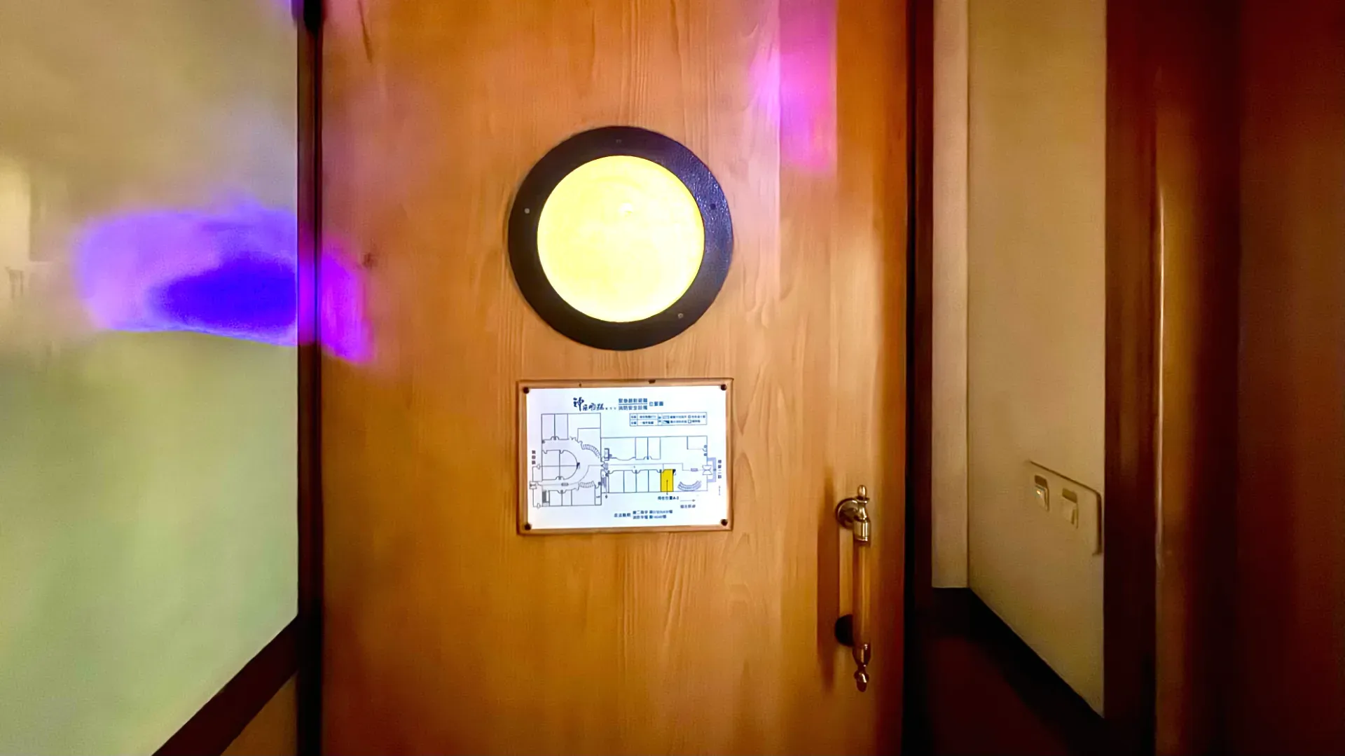 A porthole in a door, above an emergency evacuation sign.