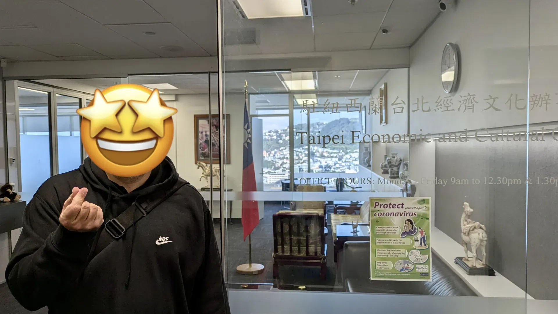 A man, with face obscured by a ‘star struck’ emoji, posing outside the Taipei Economic and Cultural Office in Wellington, New Zealand.
