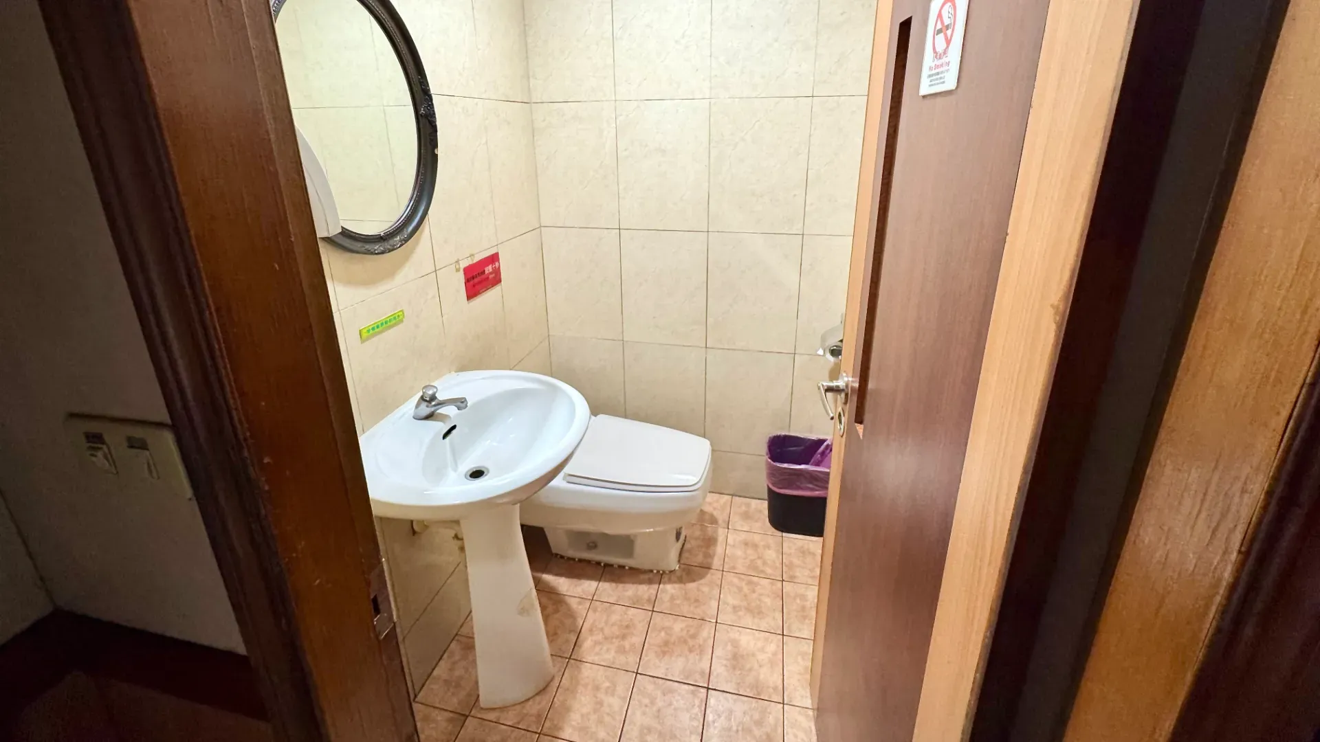 A small bathroom comprising a low western-style toilet and a hand basin.