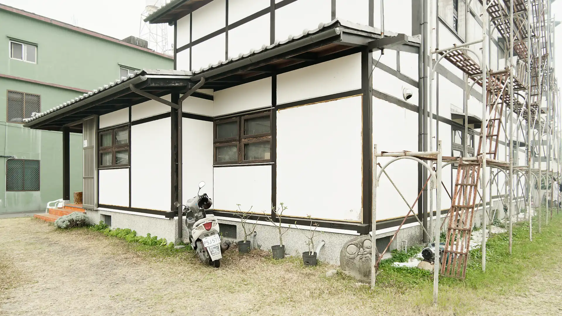 North-east corner of ‘A Book Wooden House’ in Fangliao Township, Pingtung, Taiwan. A scooter is parked along the eastern wall, and scaffolding is visible along the northern wall.
