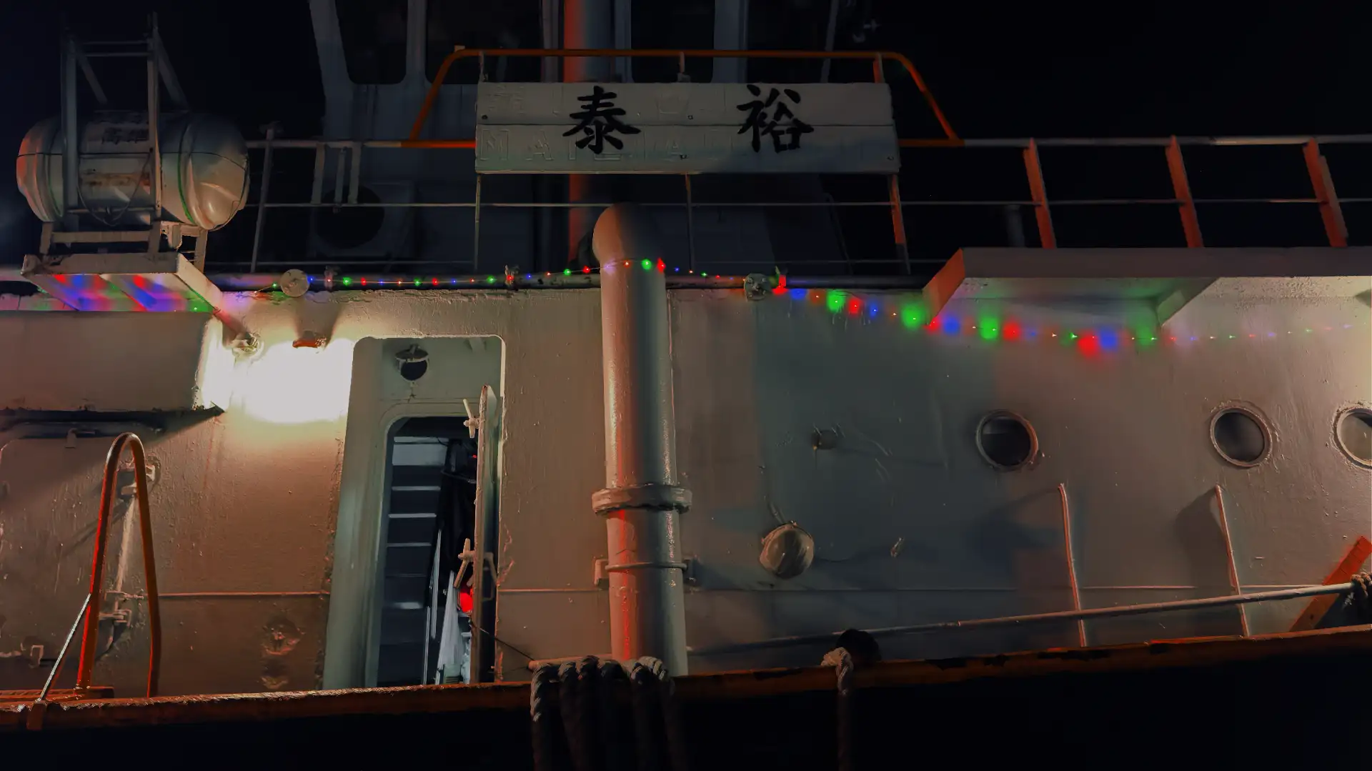 Colorful Christmas lights hanging along the side of a Port of Kaohsiung tugboat on Kaohsiung Harbor.