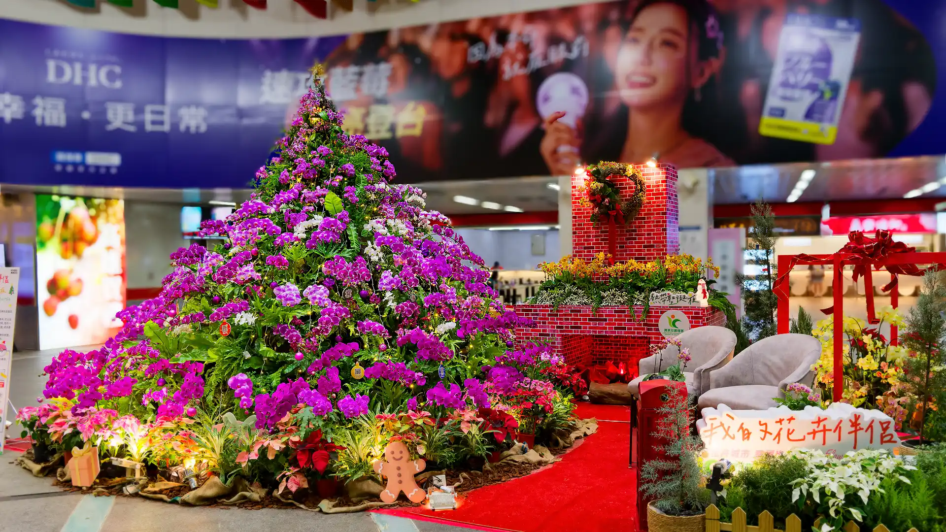 A three-meter-tall Christmas tree made of orchid flowers next to a cosy winter fireplace at Zuoying MRT Station in Kaohsiung, Taiwan.