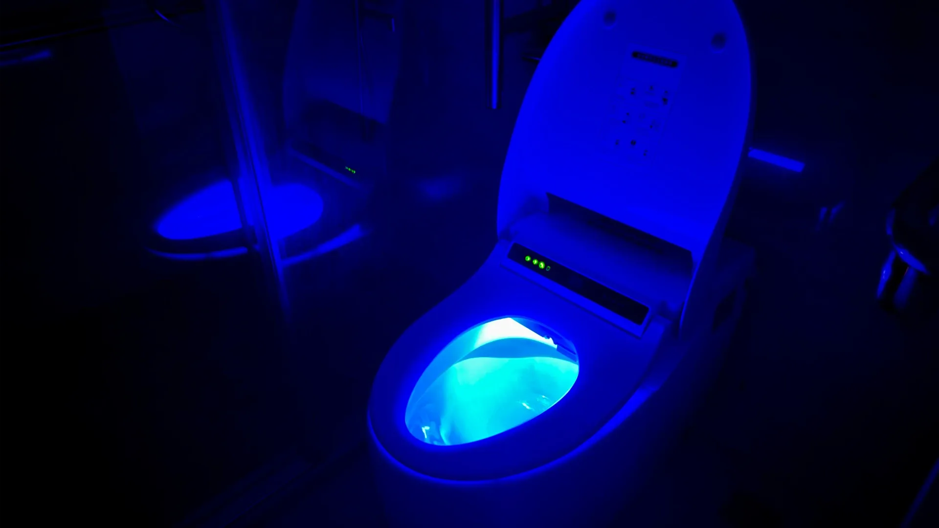 A Karat smart toilet with the lid up, in a Taiwanese bathroom at night. The inside of the bowl is illuminated in blue. The room is otherwise dark.