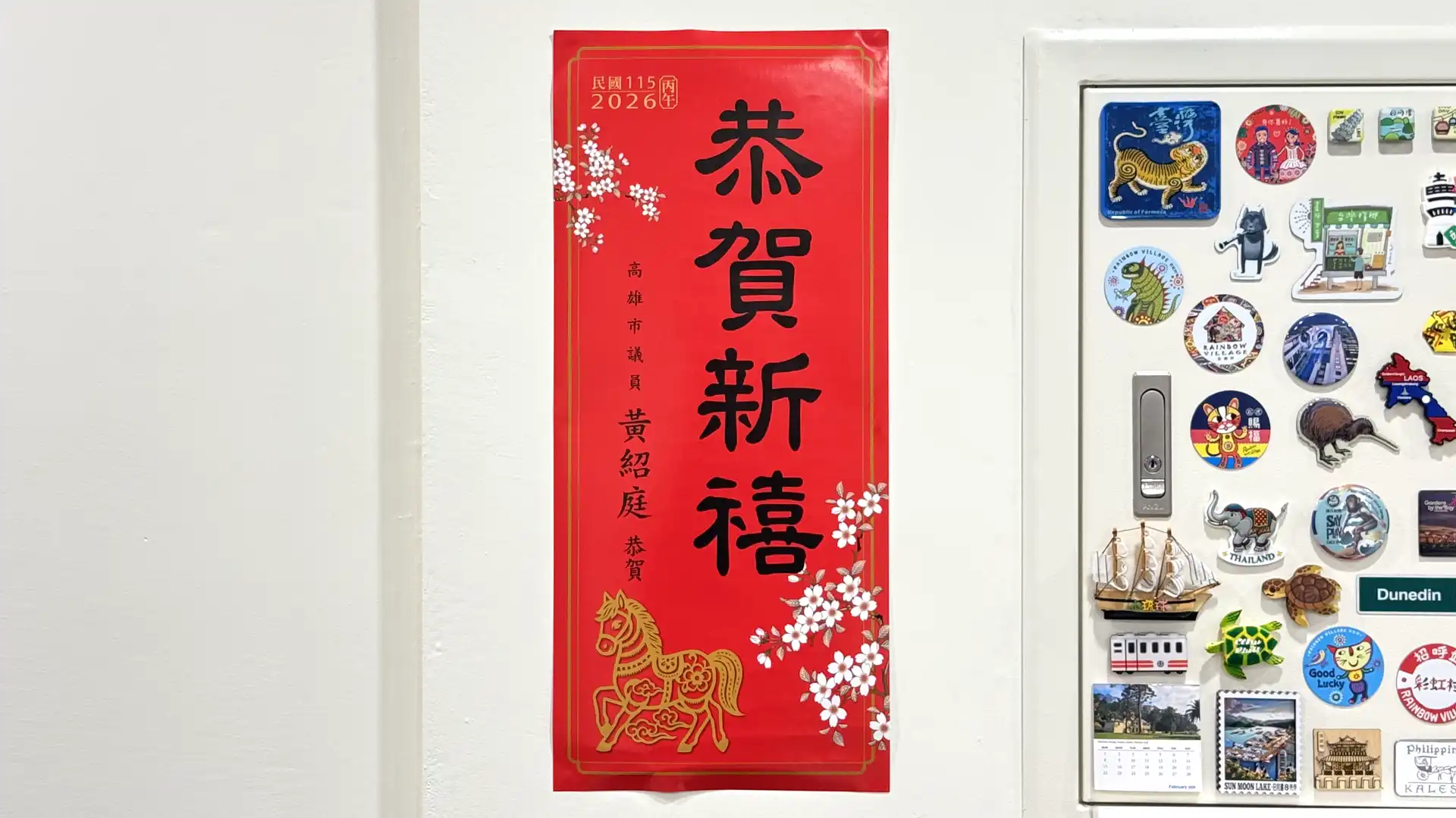 A vertical spring couplet posted on an interior wall, next to a bunch of magnets stuck to a metal door.