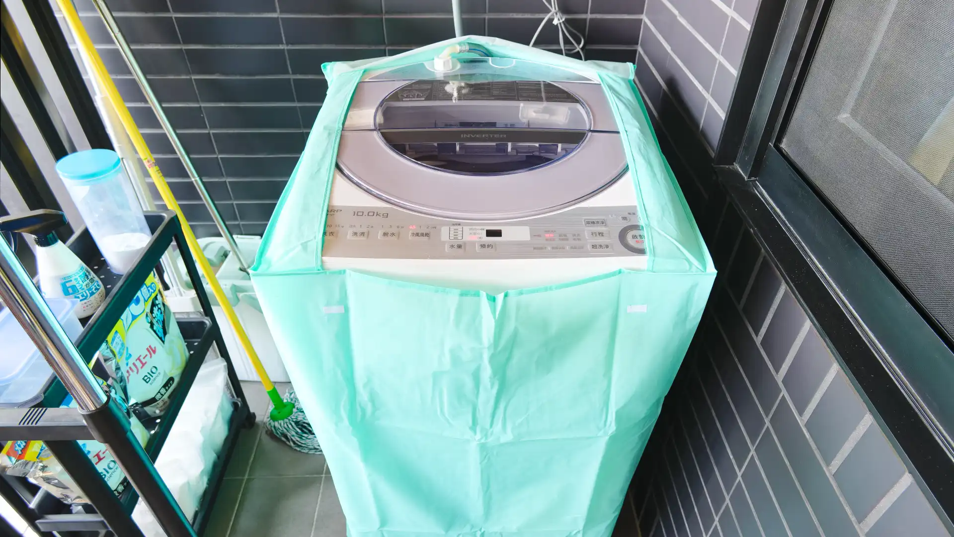 A Sharp washing machine on a Taiwanese apartment balcony. The washing machine is within a flimsy protective cover.