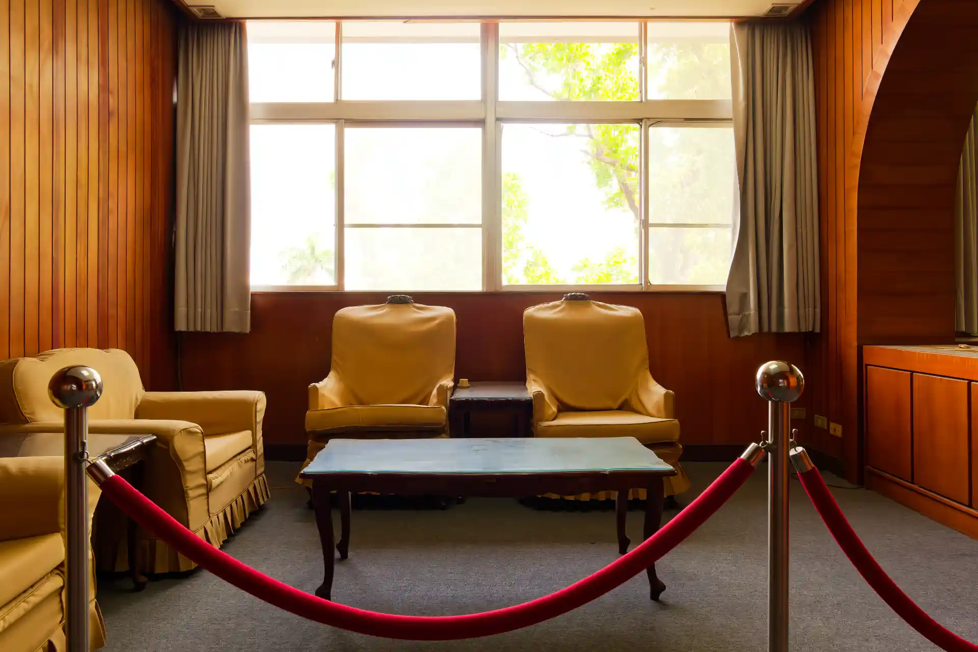 Beyond a velvet rope, four lounge chairs arranged around a central coffee table.