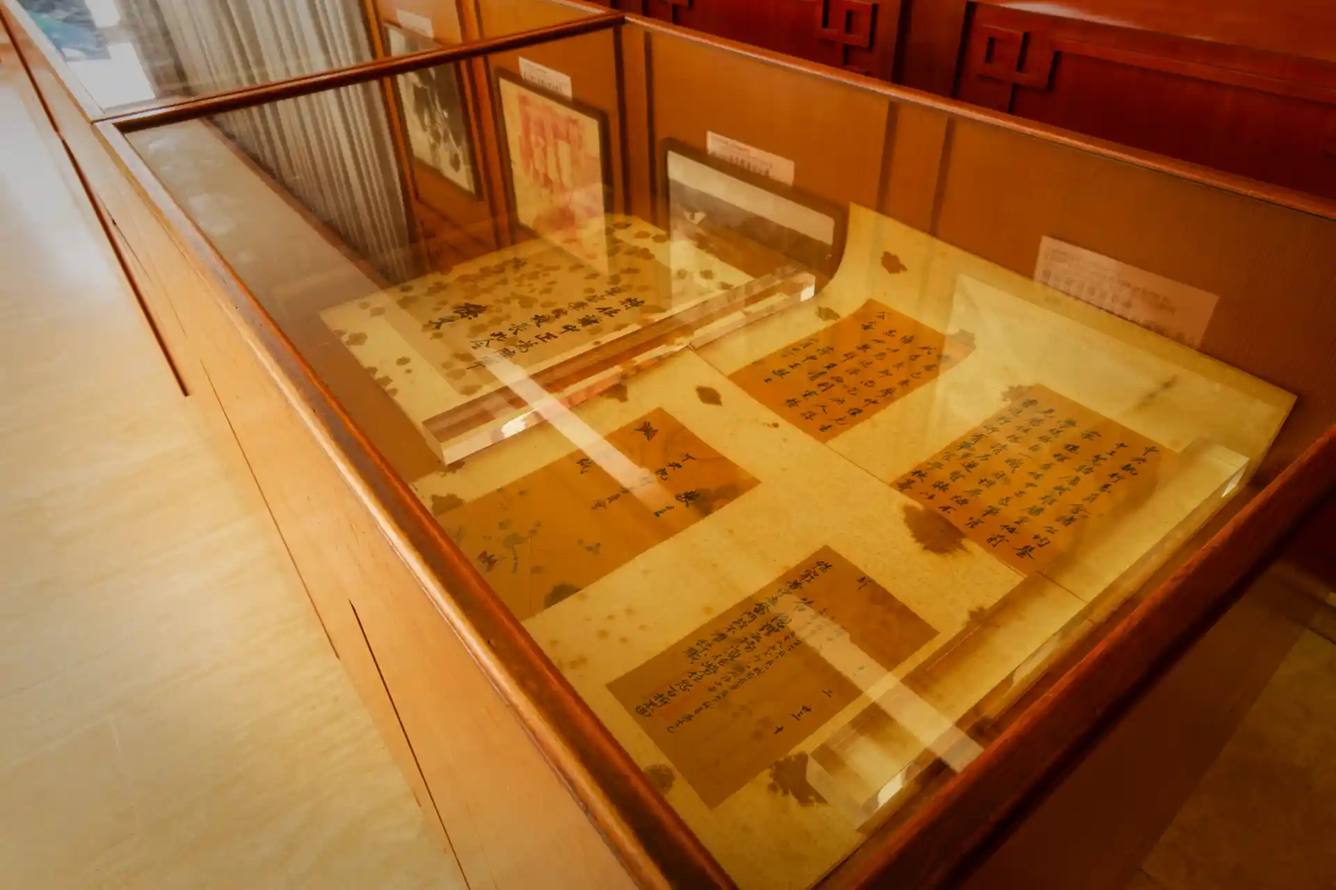 Glass-covered wooden cabinets containing old documents of Chinese script.
