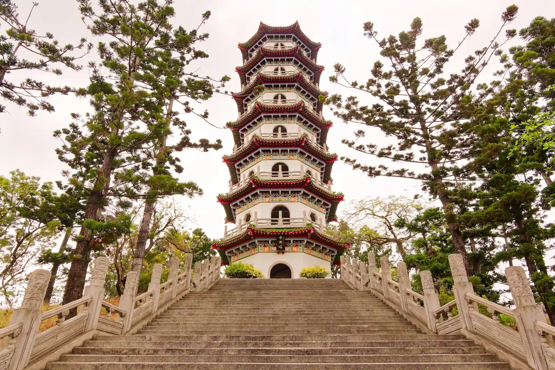 An immaculate tall seven-story Chinese pagoda surrounded by tall trees.