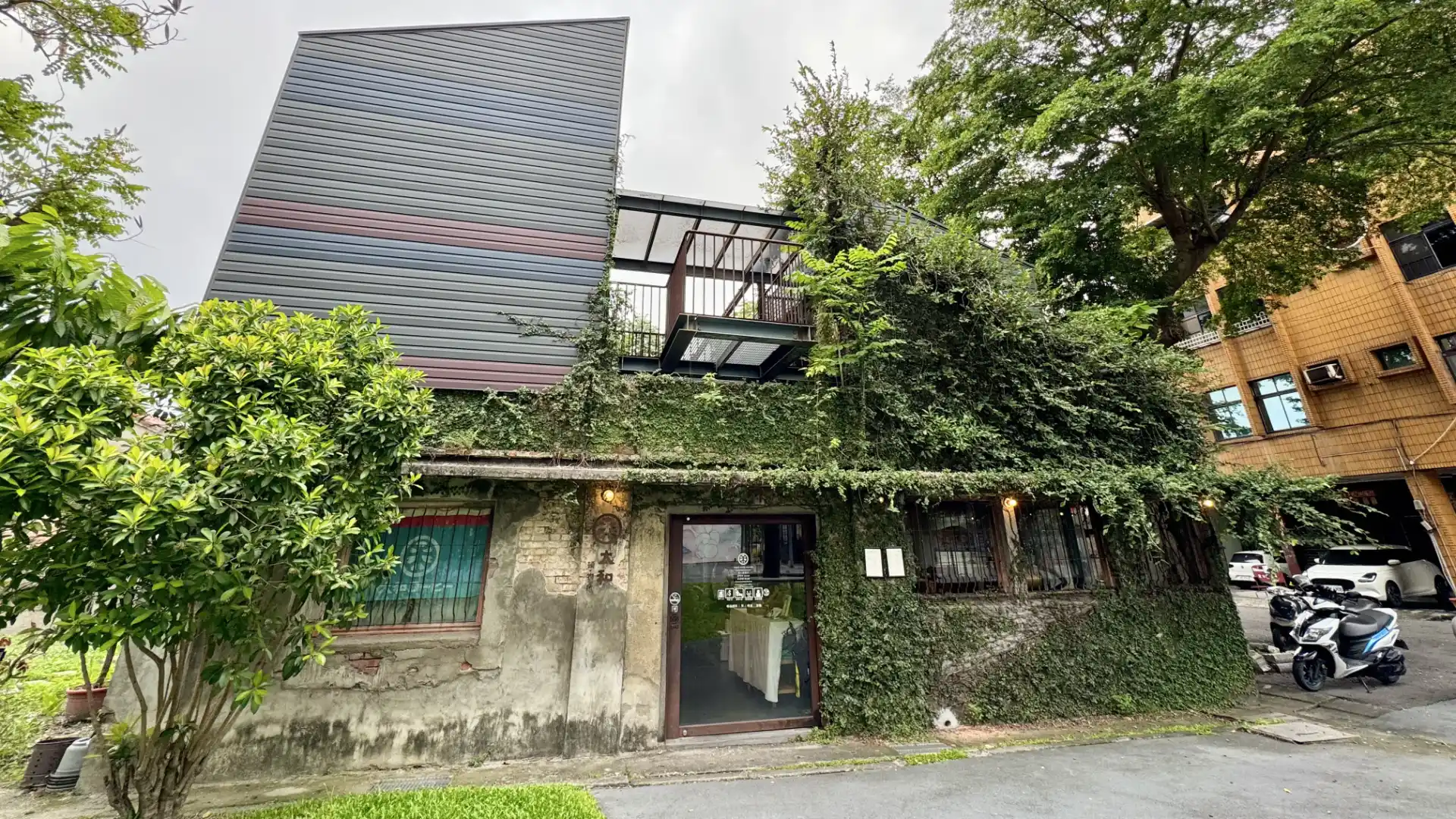 A vine-covered modern brutalist coffee shop built into the remaining shell of a former rice mill, in Zhutian Township, Taiwan.