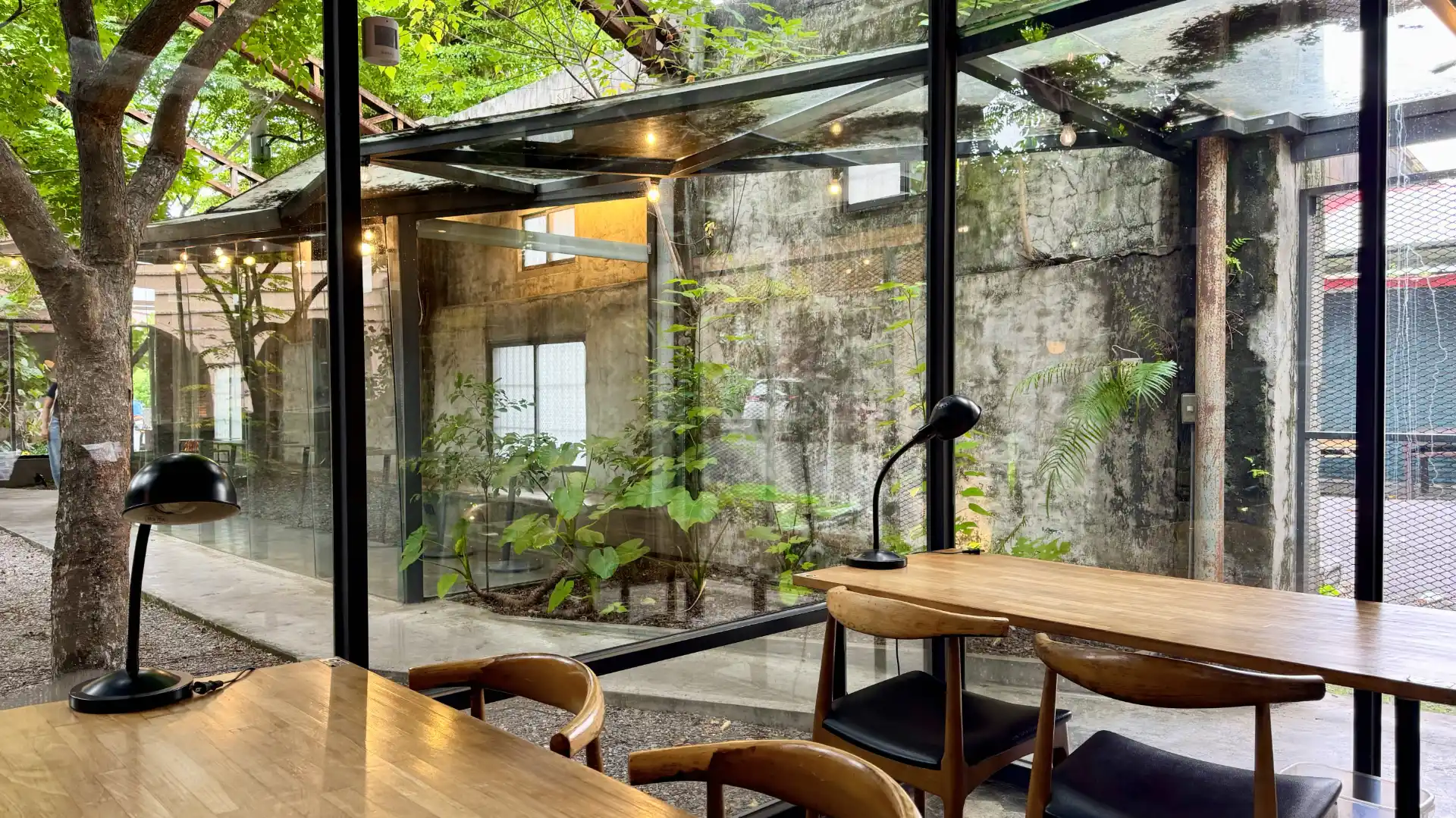 Modern, warm wooden furniture inside a glass room, built within the remains of an old rice mill in Zhutian Township, Taiwan.
