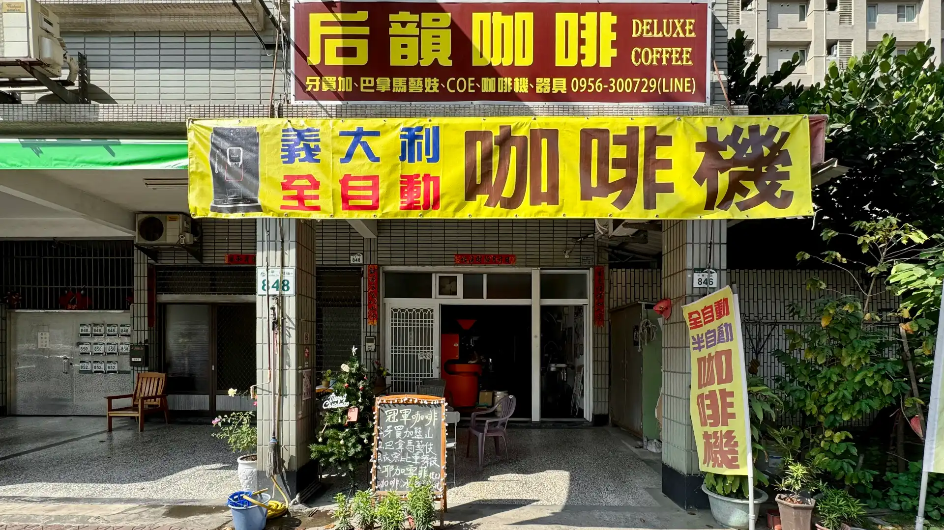 Street view of Hou Yun Coffee Roastery in Kaohsiung, Taiwan. Some potted plants are growing to the right of the frame.