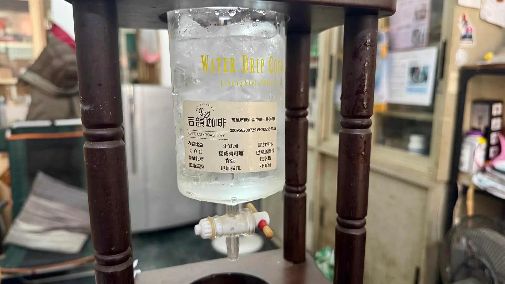 Close-up of the water reservoir of an ice drip coffee-making contraption, filled with ice cubes.